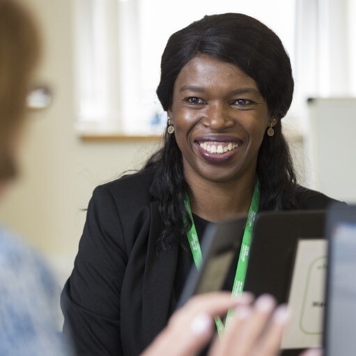 A smiling woman wearing a black suit talking to someone with their back to the camera